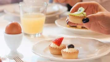 A dining table with plates of food, a glass of orange juice, and a cup.