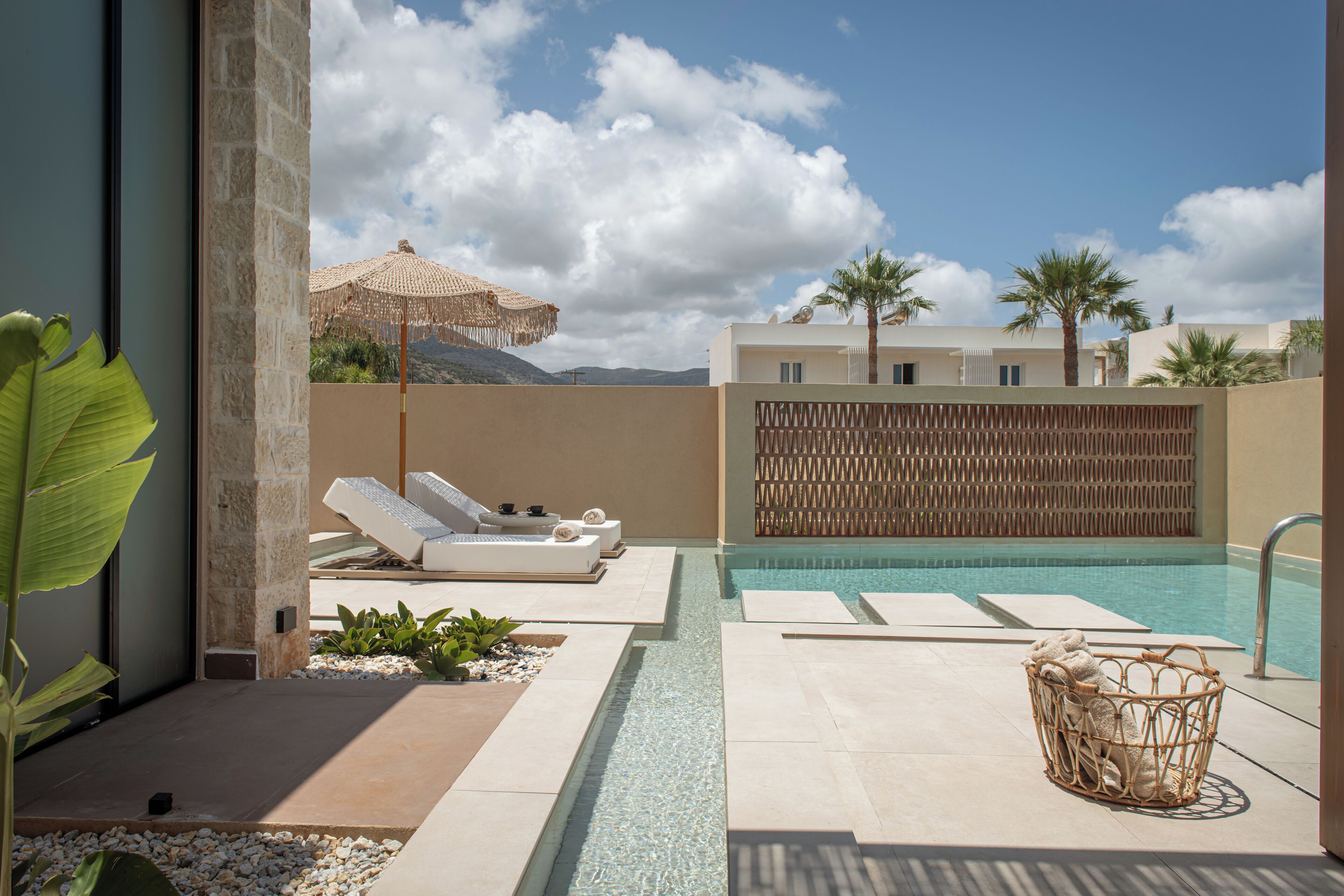 A pool area with lounge chairs, a wicker basket, and a view of the mountains.