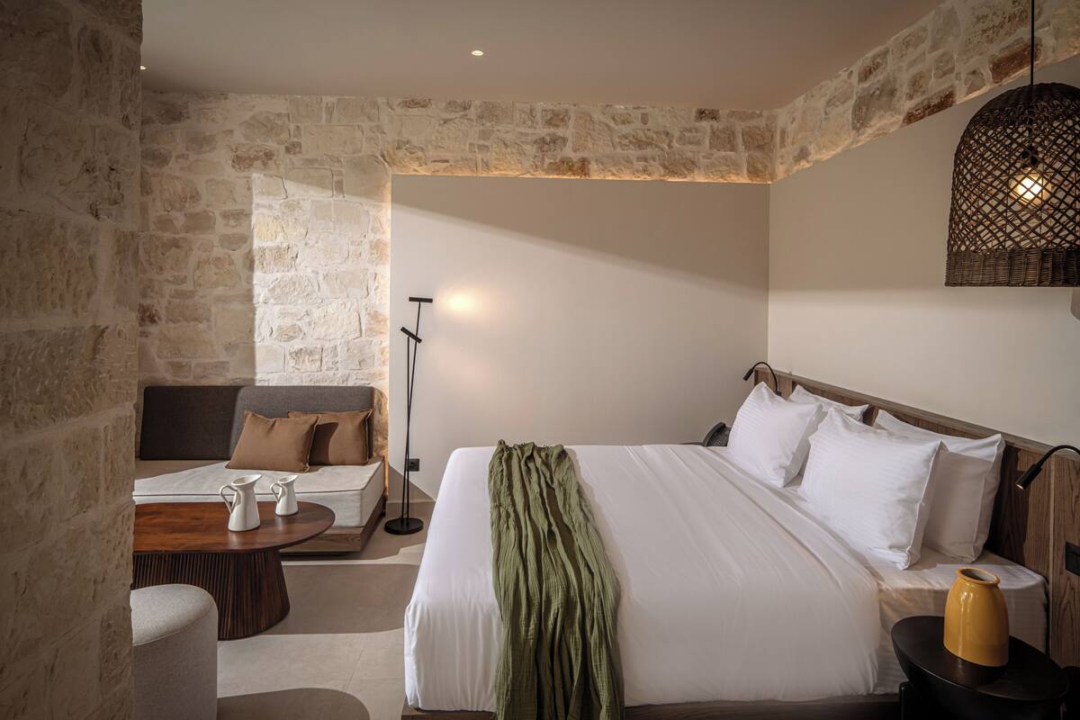 A room with a bed, a sofa, a coffee table, and a lamp.