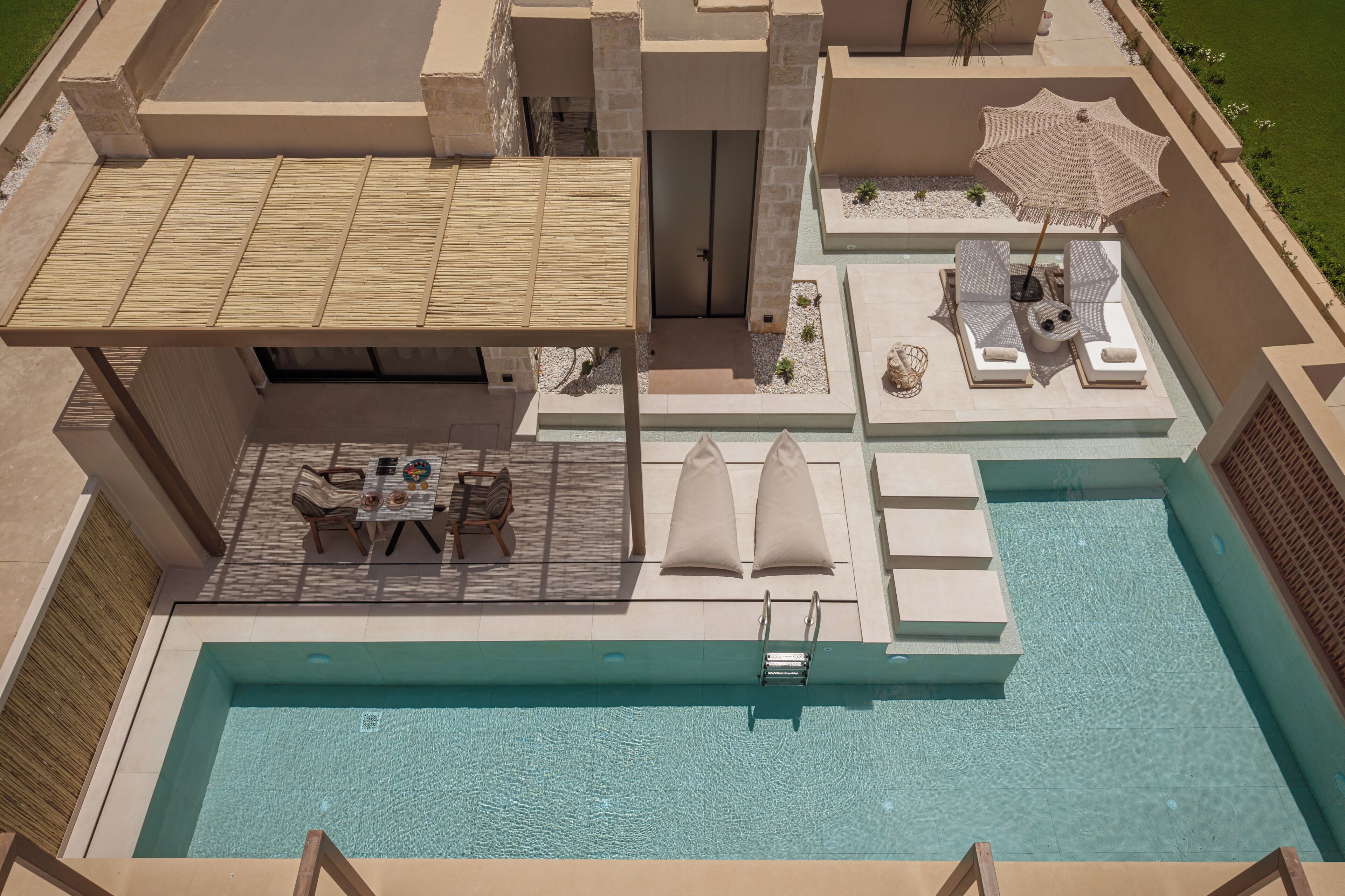 A rooftop pool area with a lounge, umbrellas, and a table with chairs.