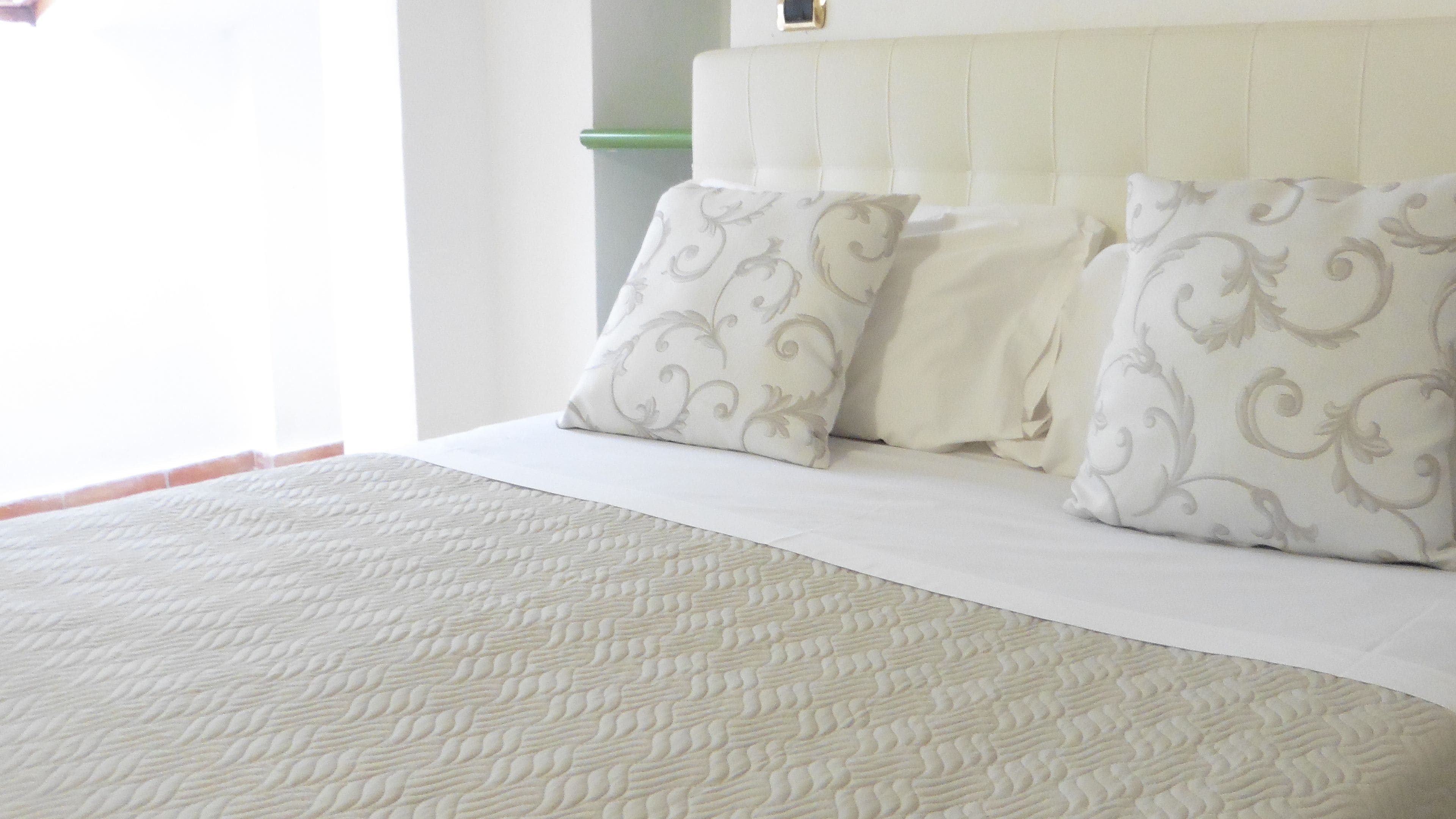 Una cama bien hecha con un edredón estampado y dos almohadas con diseño floral.