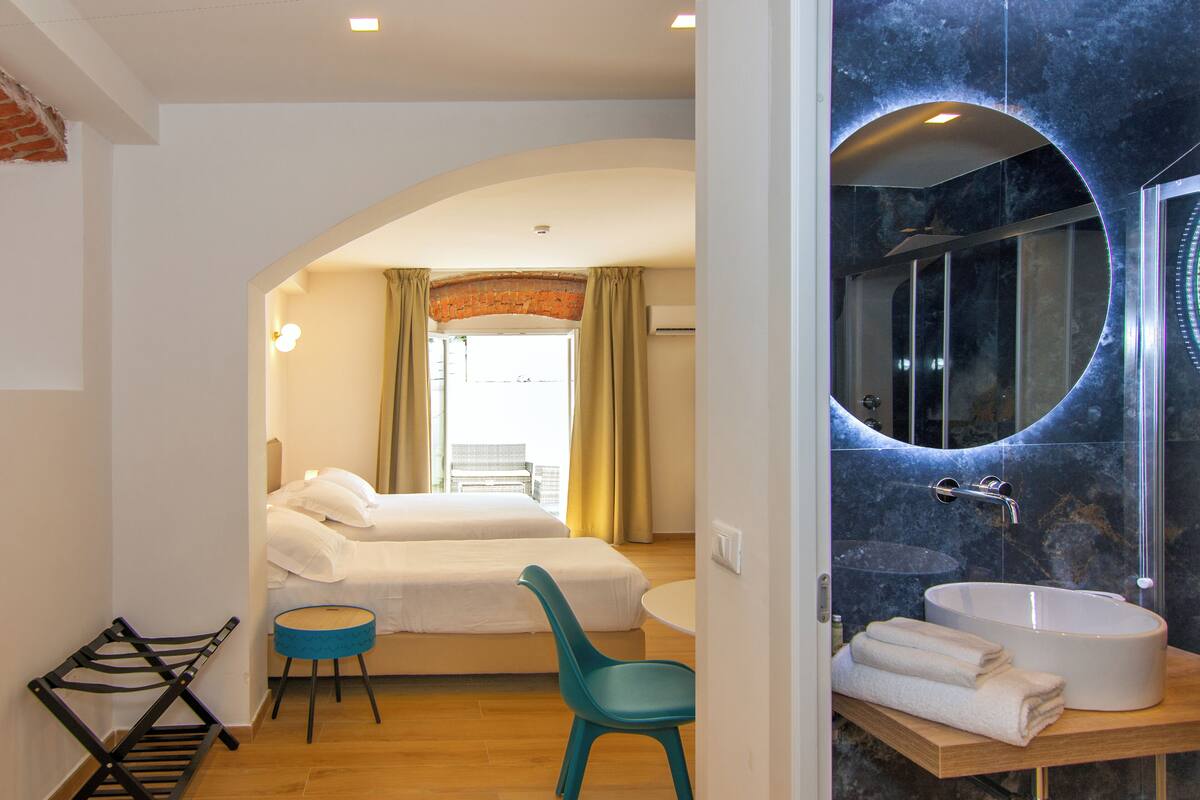 Une chambre d’hôtel avec un lit, une chaise, un lavabo et un miroir.