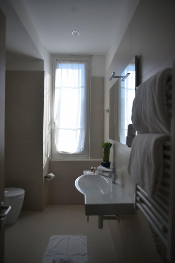 Un baño con inodoro, lavamanos y ventana con cortinas.