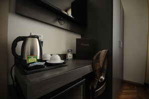 A modern hotel room with a dark wood desk, a kettle, a coffee pod, a tea pod, and a minibar. - Hotel Tirreno (Massa)