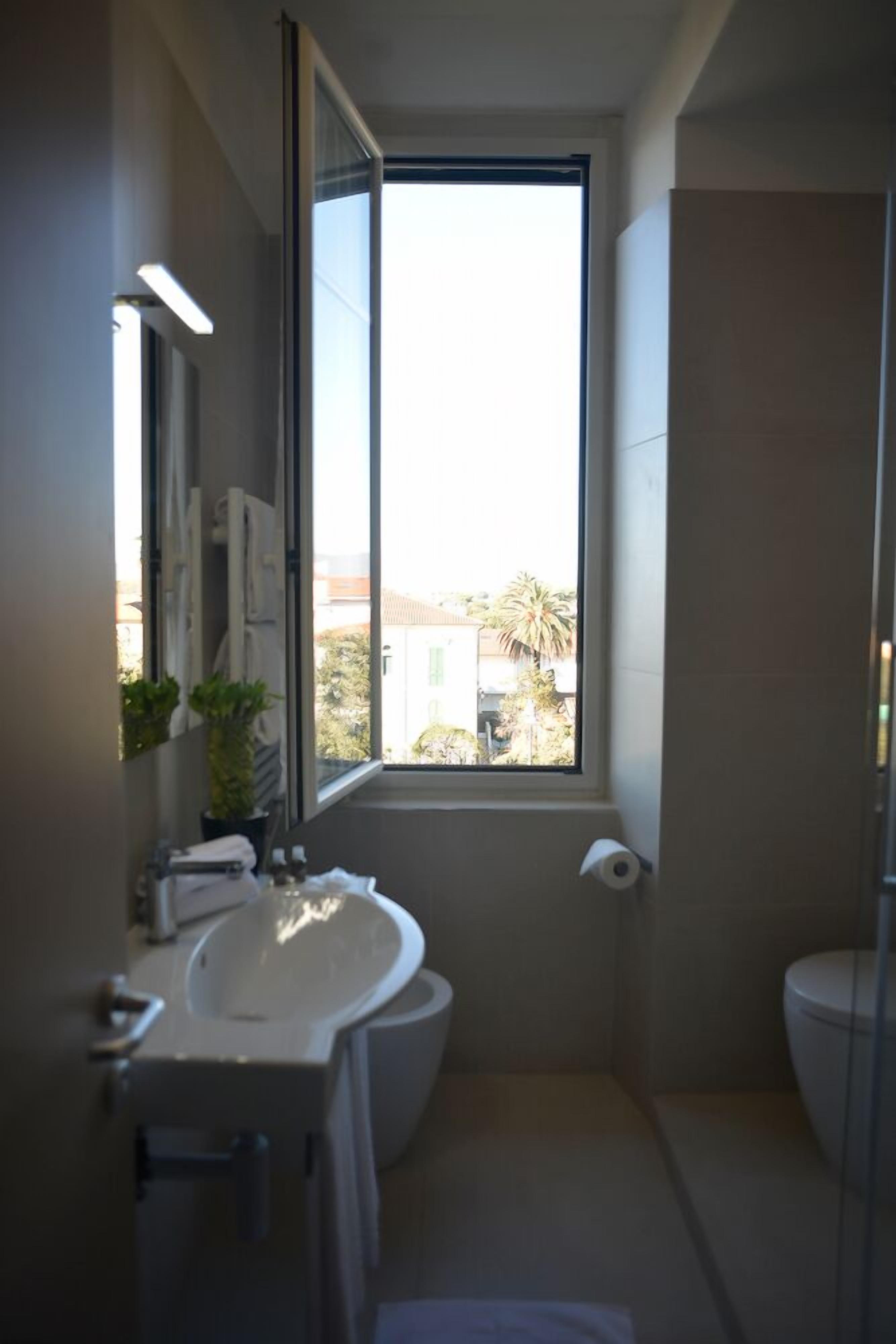 Un baño moderno con un ventanal grande, un lavamanos, un inodoro y una ducha.
