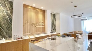 Un moderno vestíbulo de hotel con una recepción de mármol, paneles de madera y una gran pared de mármol.
