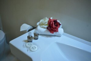A bathroom with a white sink, a white towel, and two small bottles of lotion. - Hotel Tirreno (Massa)