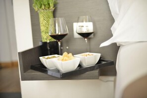 A tray with bowls of snacks and two glasses of red wine on a bedside table. - Hotel Tirreno (Massa)