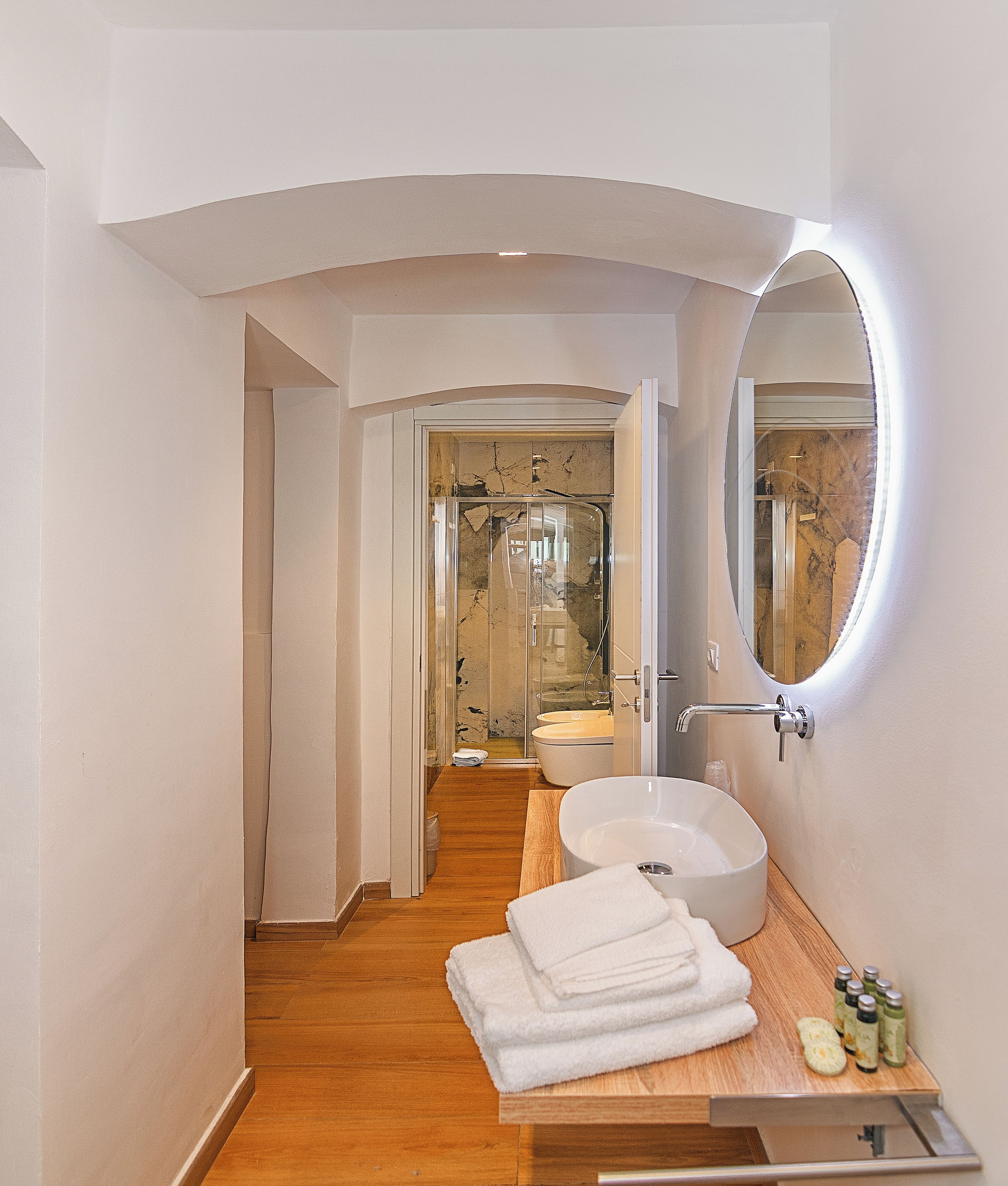 A modern bathroom with a large mirror, a round sink, and a shower area.