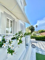 Un edificio blanco con persianas, un patio a cuadros y una bicicleta.