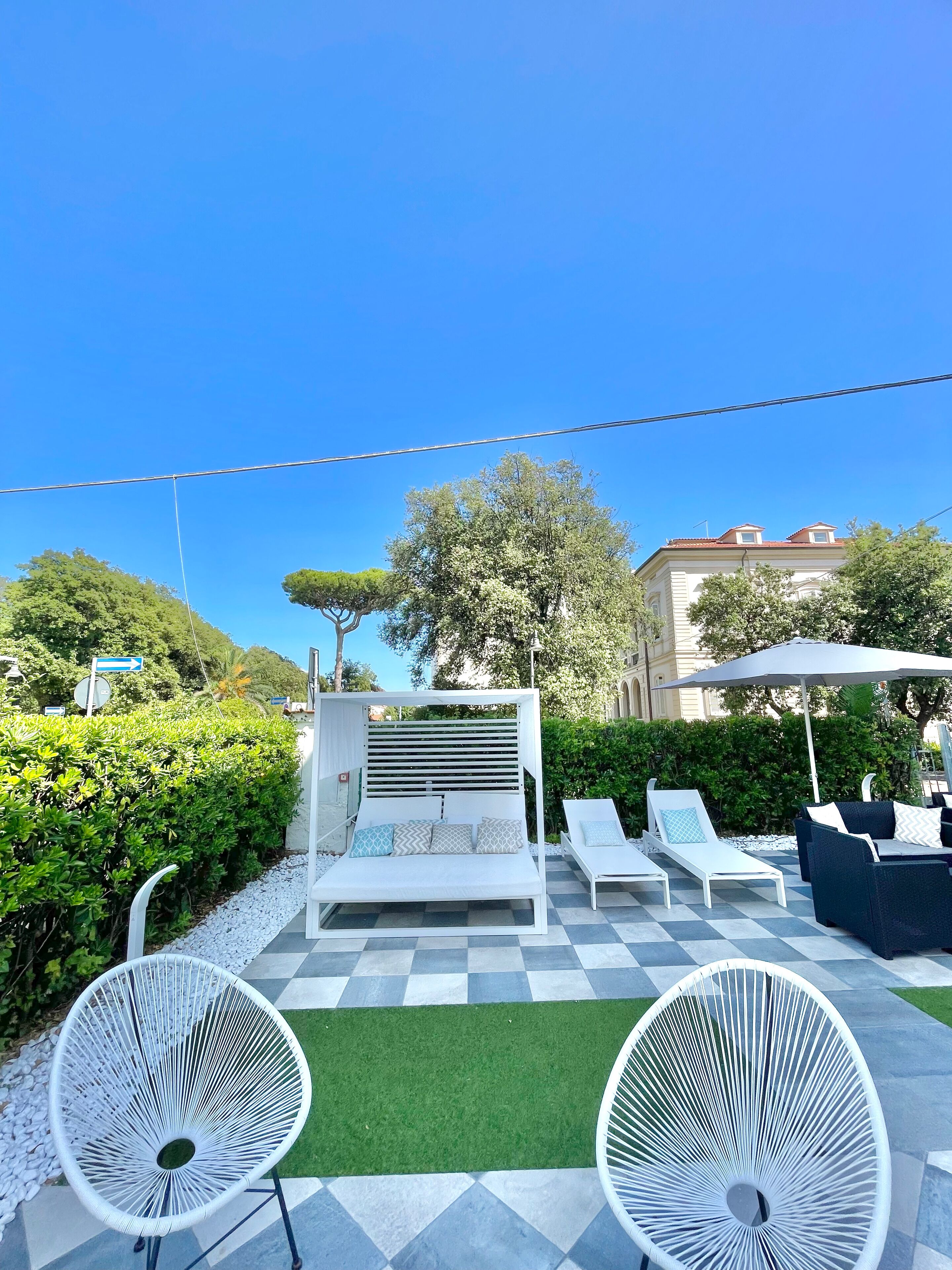 A patio with a white sofa bed, two lounge chairs, and a white chair with a circular design.