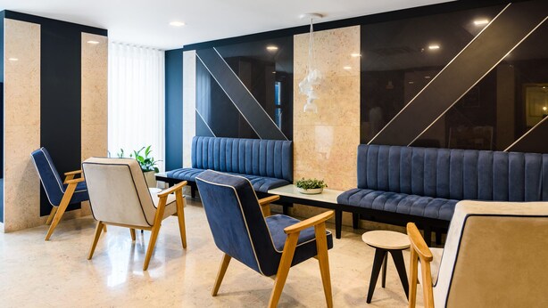 Un área de estar moderna con un sofá, sillas y una mesa.