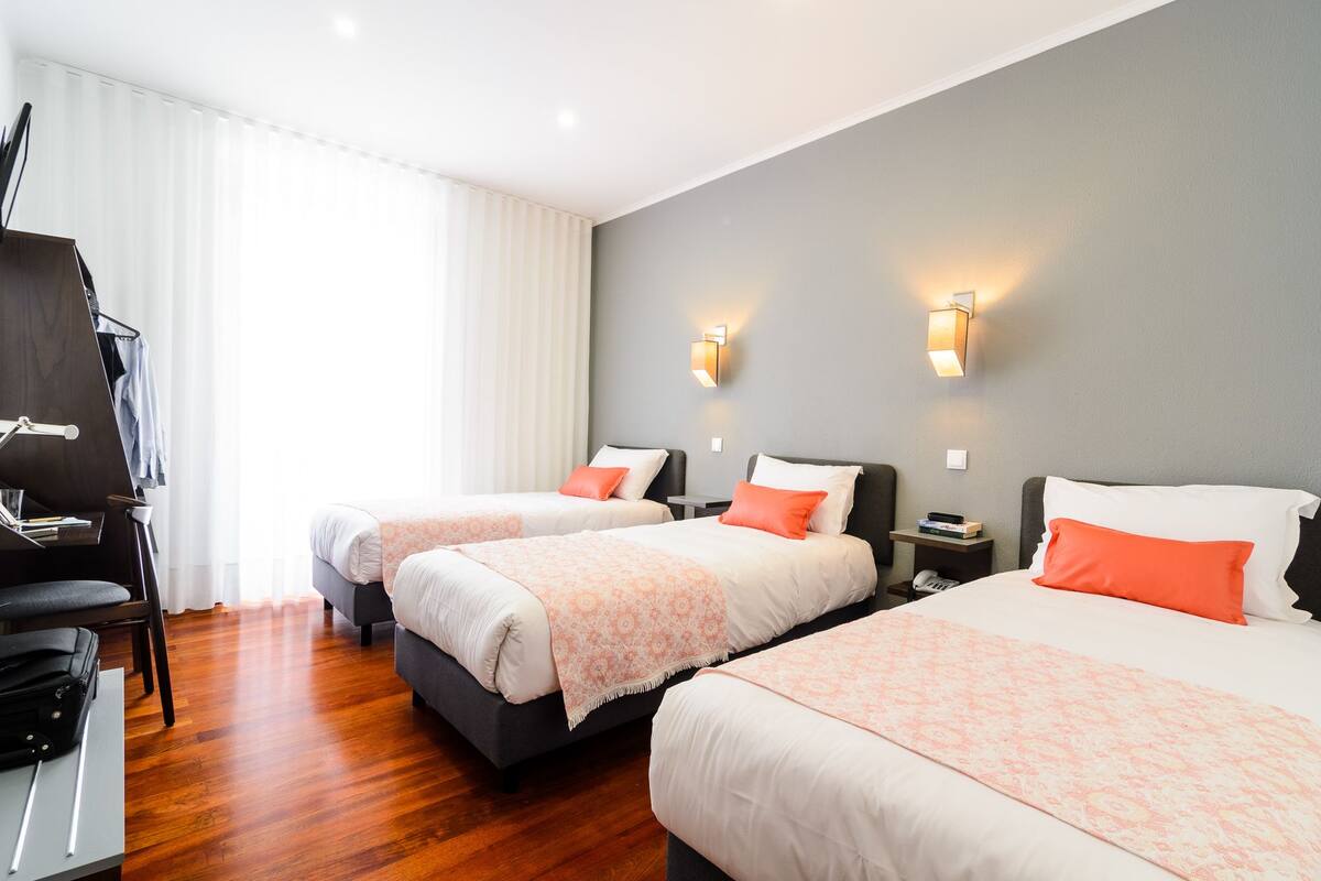 Une chambre d’hôtel avec deux lits, un bureau et une chaise.
