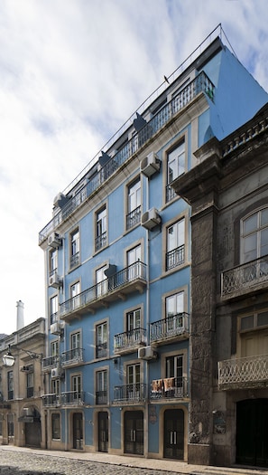 Un edificio a più piani con balconi, condizionatori e una strada acciottolata.