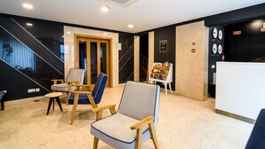 Un interior moderno con una escalera, sillas de madera, una mesita y una estantería.
