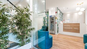 Un espace d’accueil moderne, avec des murs en verre, un comptoir d’accueil et un escalier.