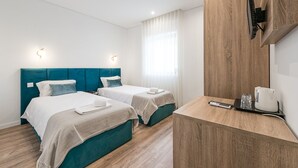 Une chambre d’hôtel avec deux lits, un bureau en bois, un téléviseur à écran plat et une fenêtre avec des rideaux.