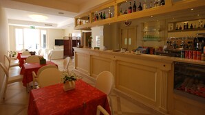 Un comedor de hotel con mesas, sillas, una barra con estantes llenos de botellas y un televisor.