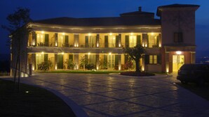 Un edificio de dos pisos con un patio amplio, varios balcones y una entrada bien iluminada.