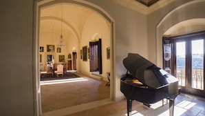 A grand room with a piano, arched ceilings, and a view through a large window.