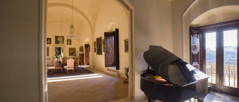 A grand room with a piano, arched ceilings, and a view through a large window.