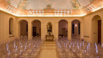 Un vestíbulo amplio con filas de sillas, arcos y un techo decorativo.