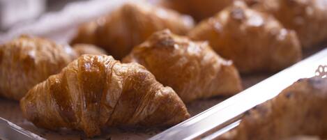 A tray of golden-brown croissants on a white surface.