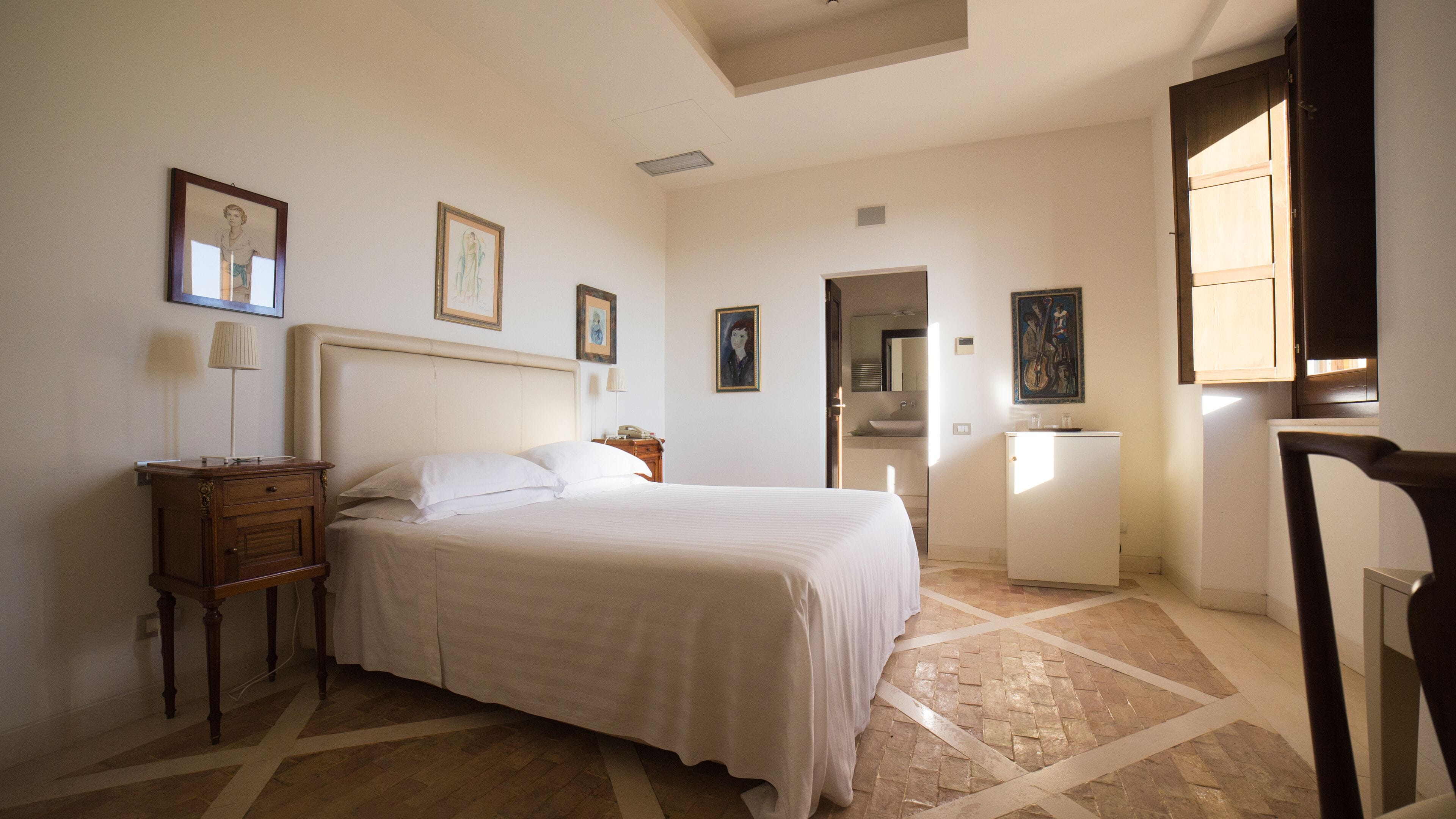 Un dormitorio ordenado con cama, mesita de noche, lámpara y un pequeño armario.