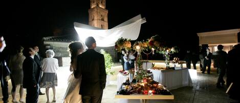 A wedding reception with a table set for guests, a backdrop, and a tower in the background.
