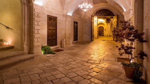 A stone-paved corridor with arched ceilings and a chandelier.
