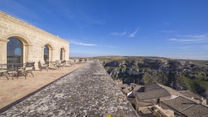A stone building with outdoor seating and a view of a valley.