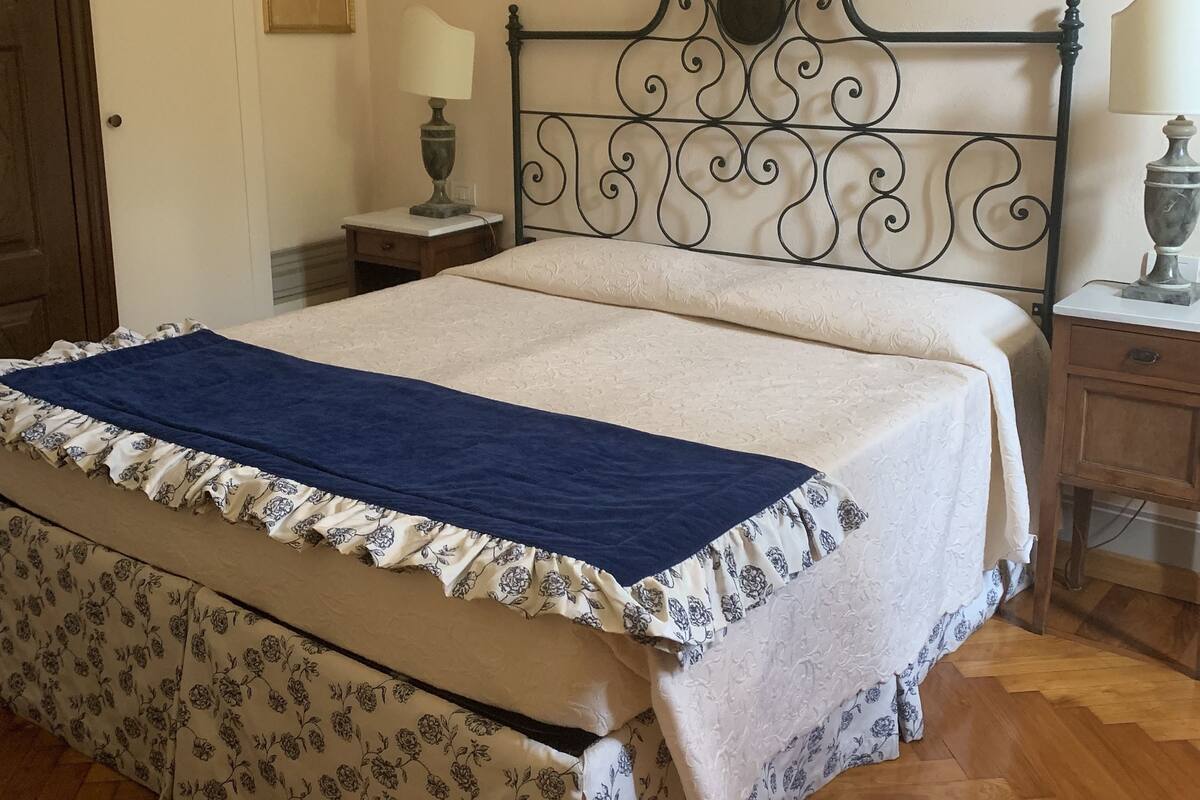 Un lit bien fait, avec une couvre-lit à motifs floraux et une couverture bleue.