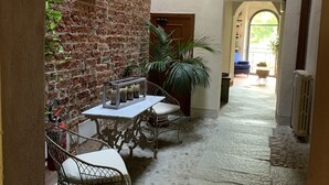An outdoor patio area with a brick wall, a table with chairs, and a potted plant. - Castello La Rocchetta (Sandigliano)