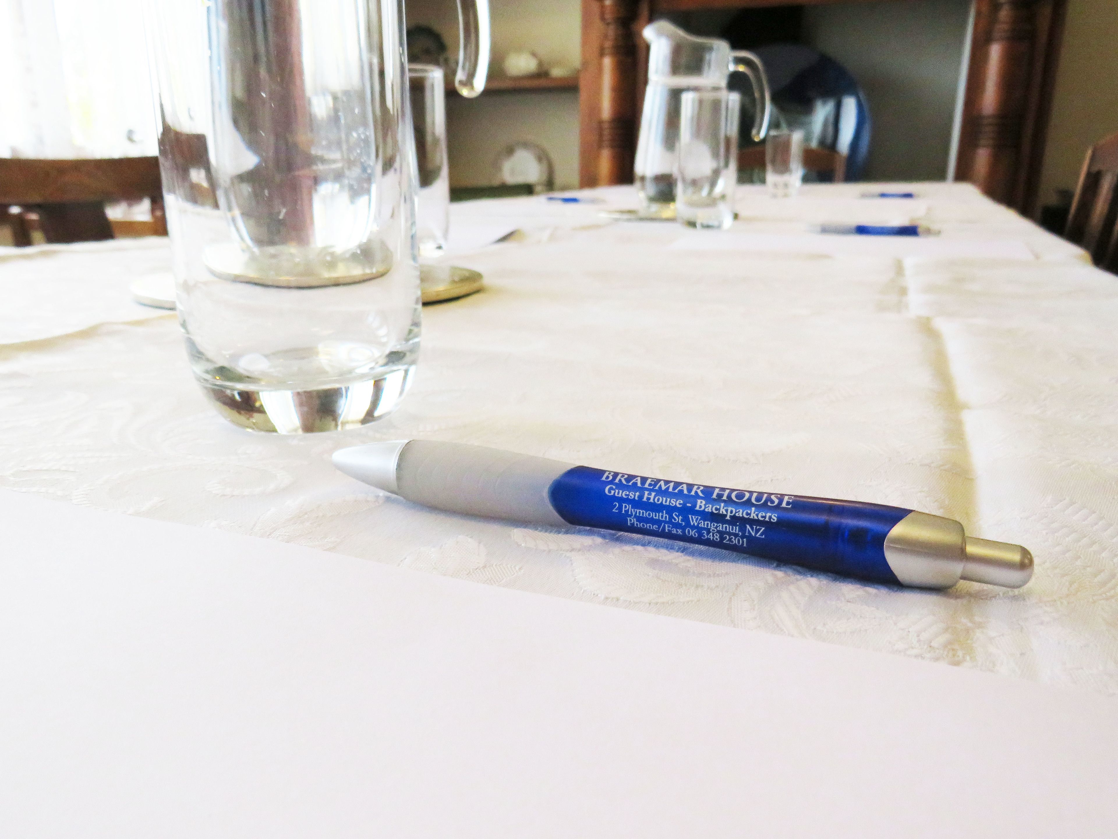 Ein Tisch mit einem Stift, einer Karaffe und einem Glas Wasser.