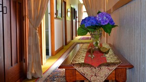 Un couloir avec une table en bois, un vase de fleurs et un chemin de table rouge.