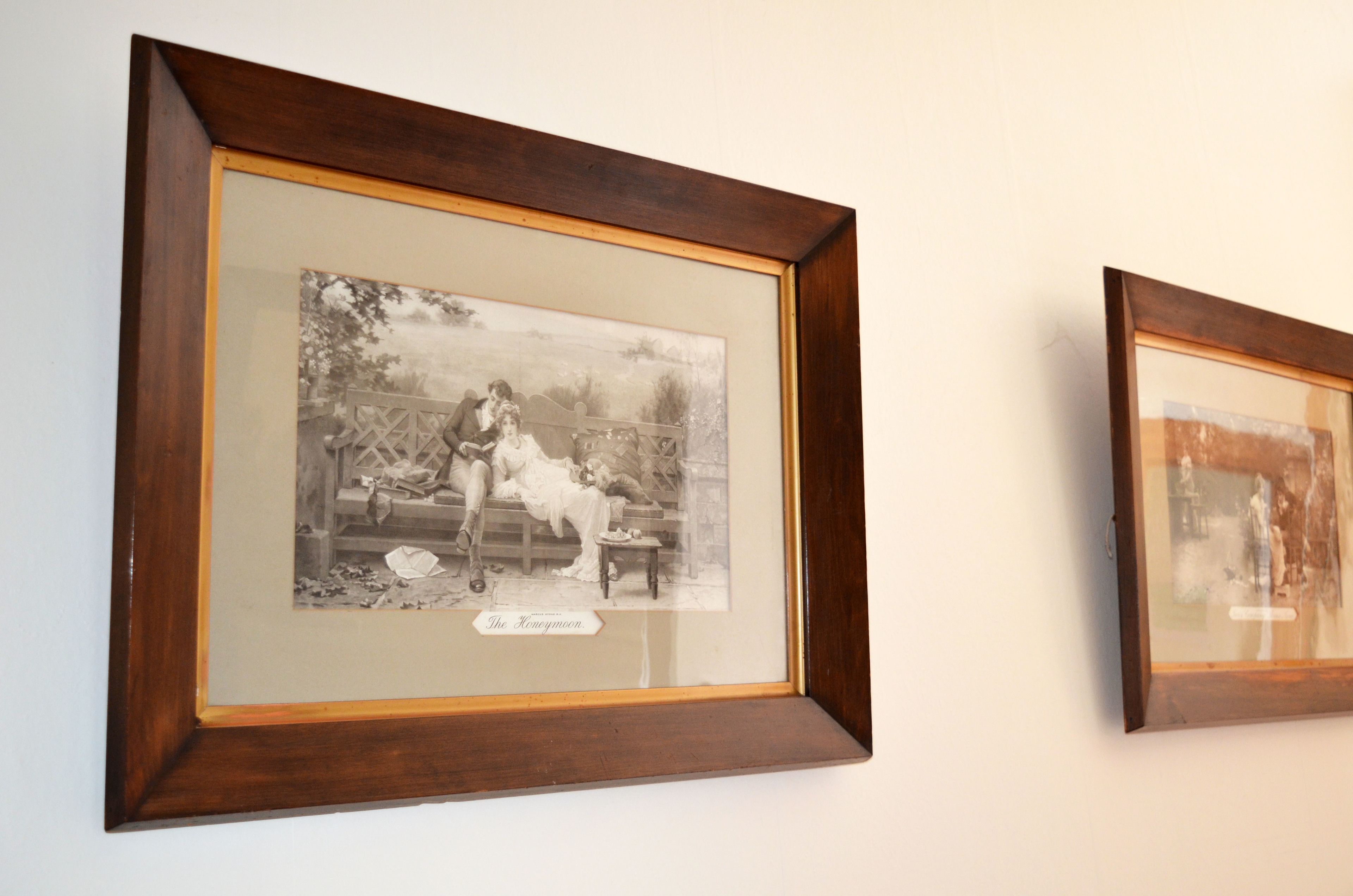 Twee zwart-witfoto's in lijsten aan een muur.