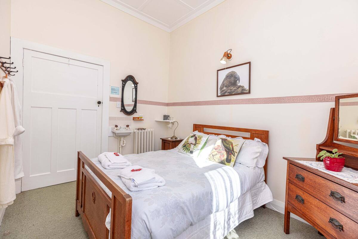 Une chambre bien rangée, avec un lit, une table de chevet, une commode et une porte.