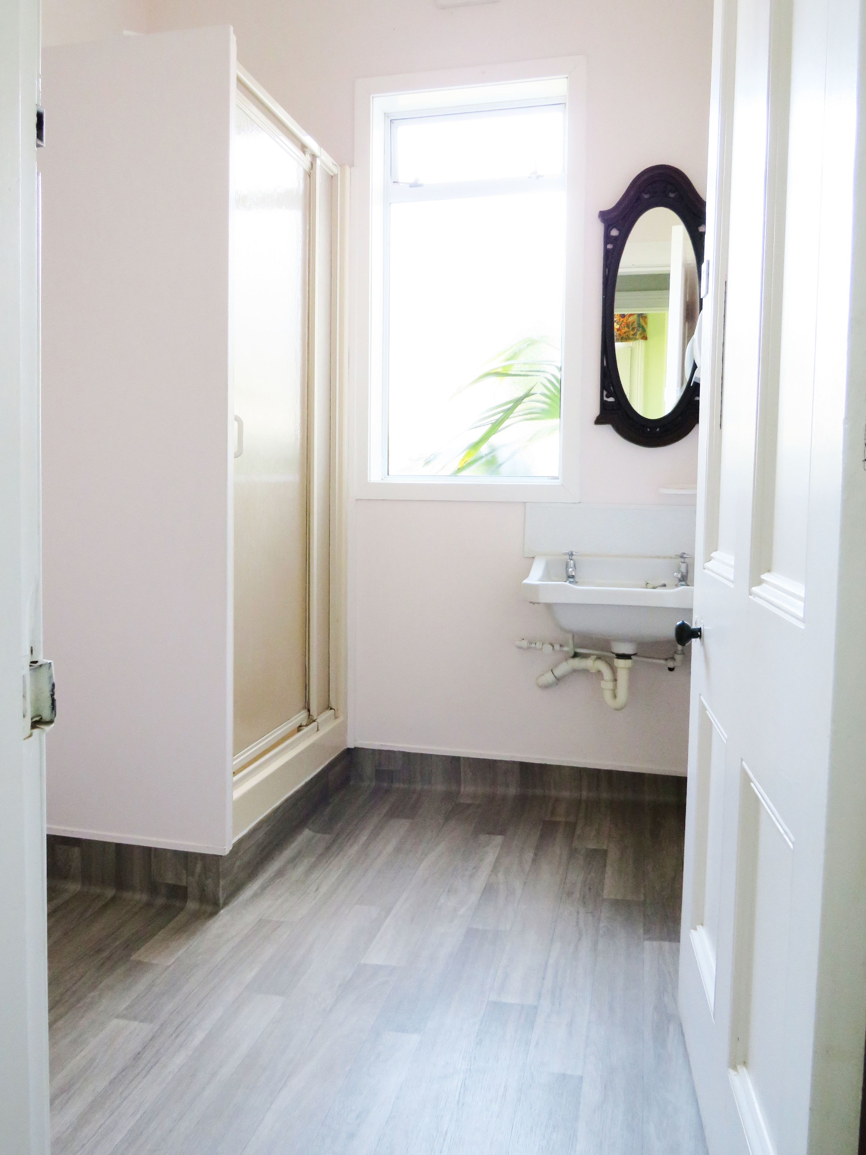 Ein Badezimmer mit Dusche, Waschbecken und Fenster.