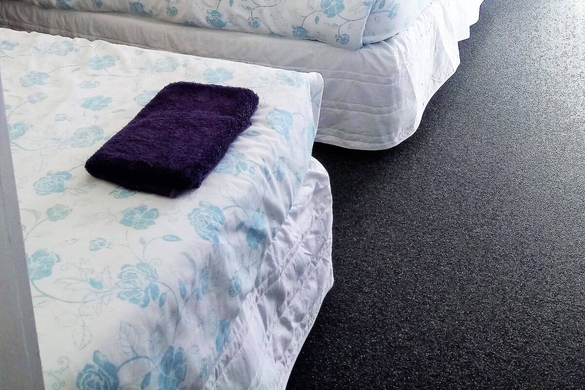 Une chambre avec des lits superposés et deux lits simples, chacun agrémenté de draps et d’oreillers à motifs floraux.