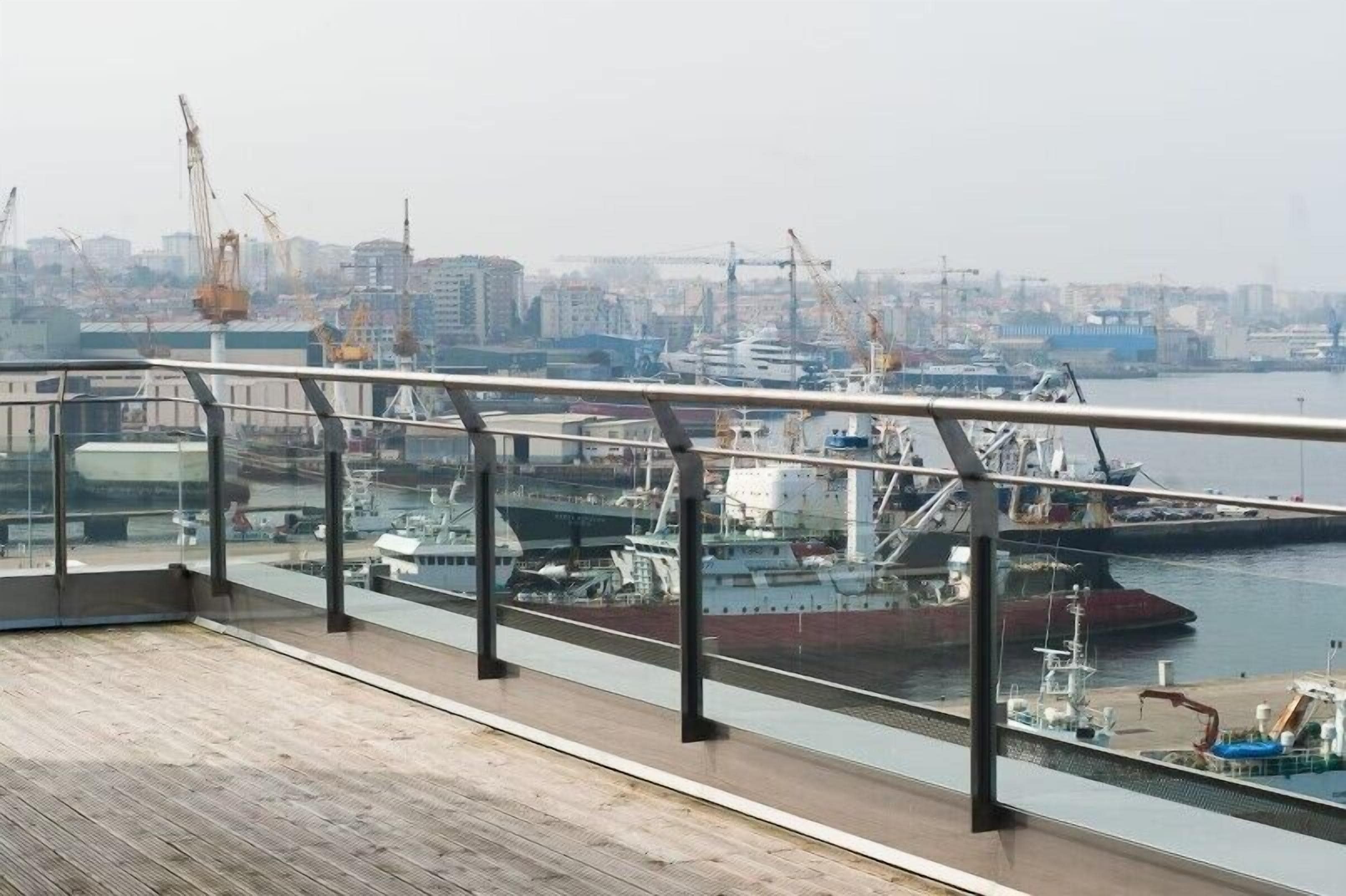 Vista desde un balcón con vistas a un puerto deportivo con barcos y grúas.