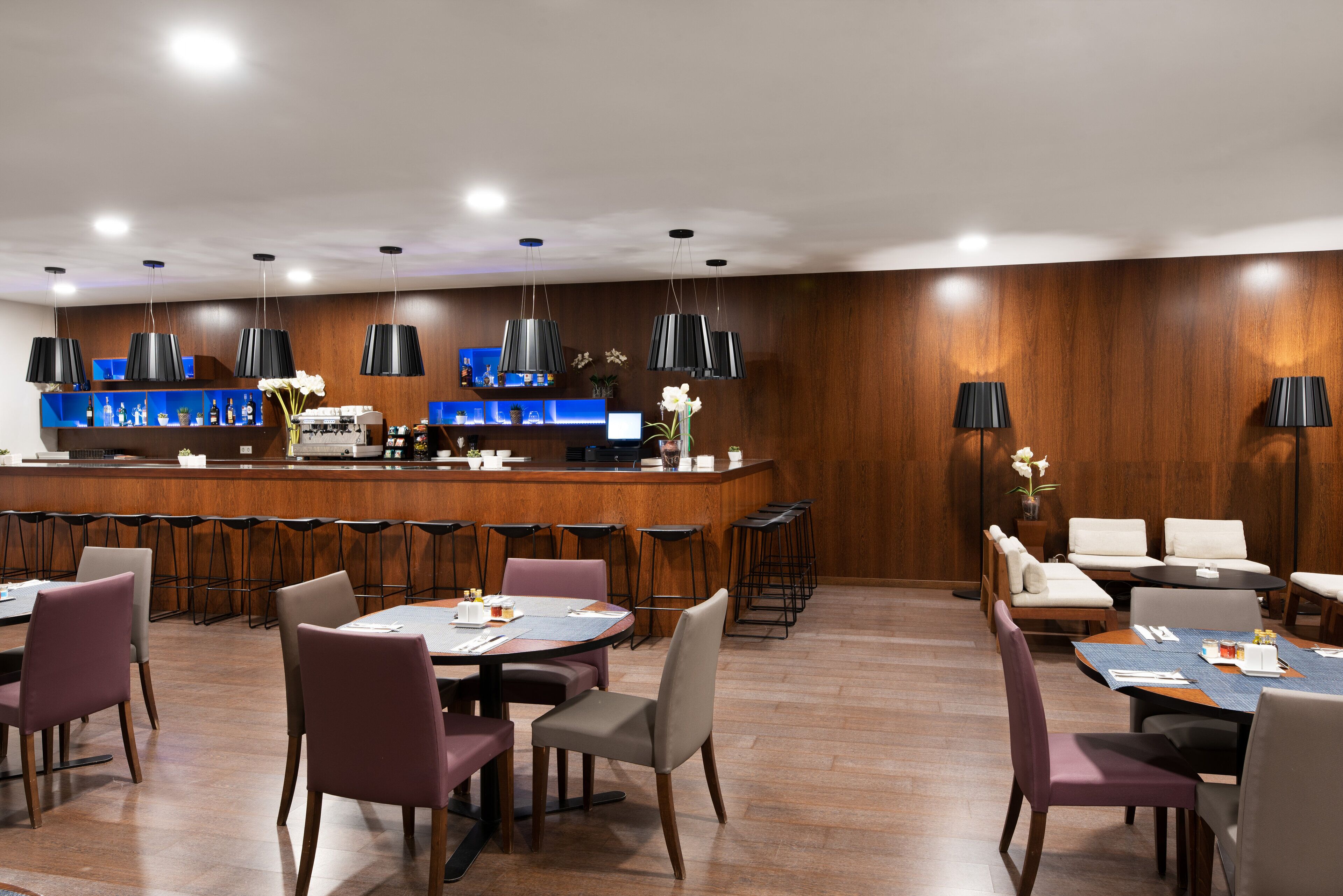 Un moderno vestíbulo de hotel con zona de bar, asientos y una recepción.