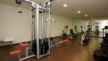 Un gimnasio con diversos equipos de ejercicio, como una máquina Smith, cintas de correr y bicicletas estáticas.