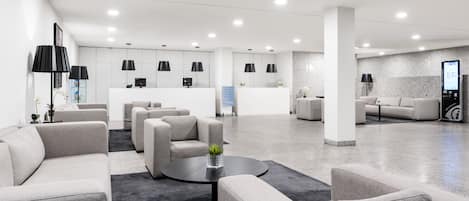 A modern lobby with sofas, a reception desk, and pendant lighting.