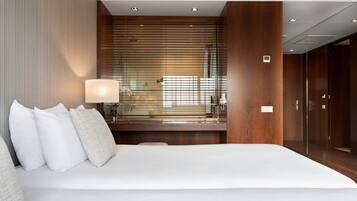 Una moderna camera d'hotel con un letto grande, un comodino con una lampada e vista panoramica da ampie finestre a tutta parete.