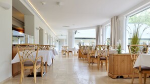 Un comedor amplio con techos altos y ventanas grandes, que presenta sillas y mesas de madera.