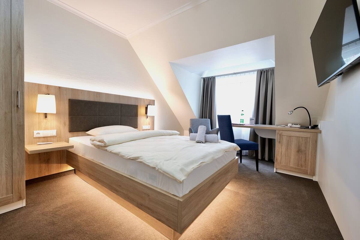 Ein modernes Hotelzimmer mit einem großen Bett, einem Schreibtisch und einem Fernseher.