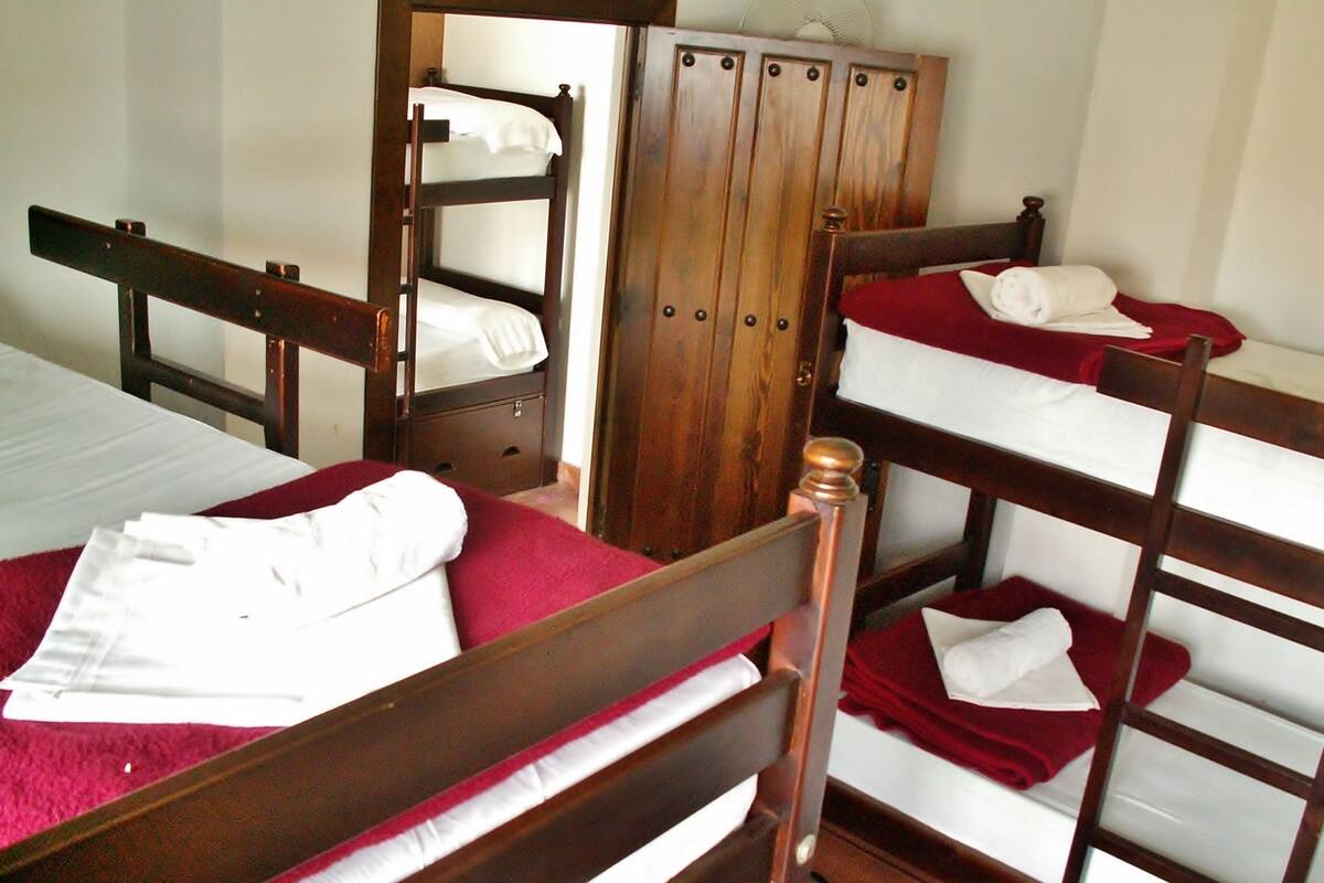 Un dormitorio con literas, un armario de madera y una colcha roja.