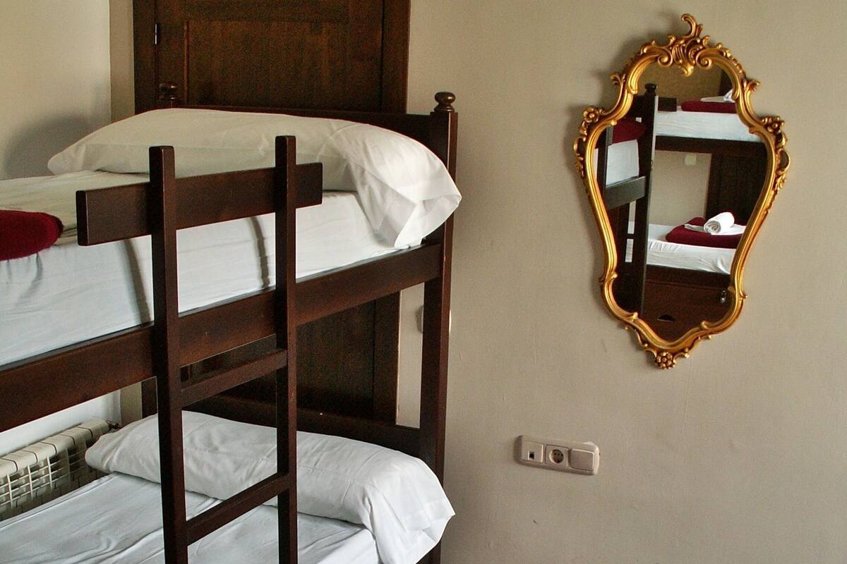 Una cama litera con cabecera de madera, un espejo con marco decorativo y un suelo de baldosas con diseños de estrellas.
