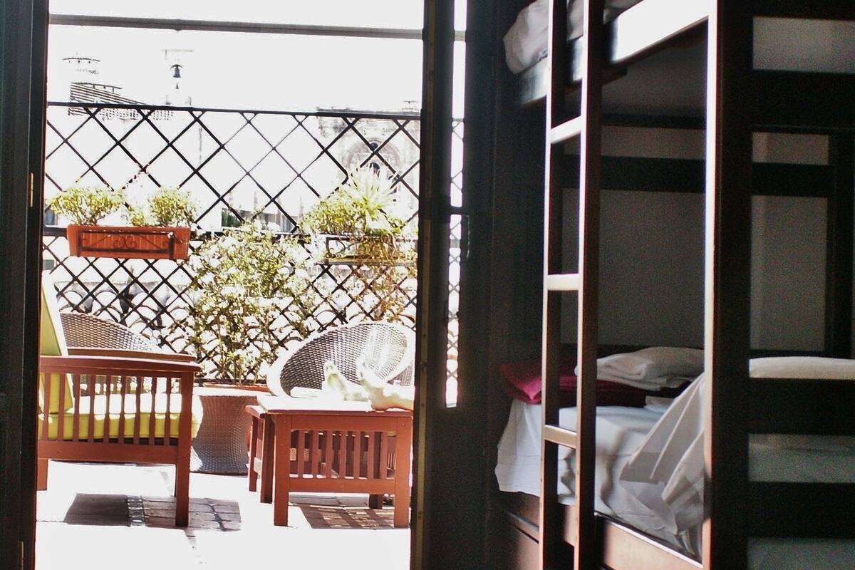 Una habitación con una litera, una silla de madera y una mesita.