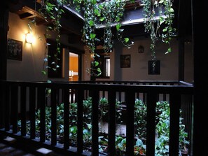 Un balcone con ringhiera in legno, circondato da piante e viti rigogliose.